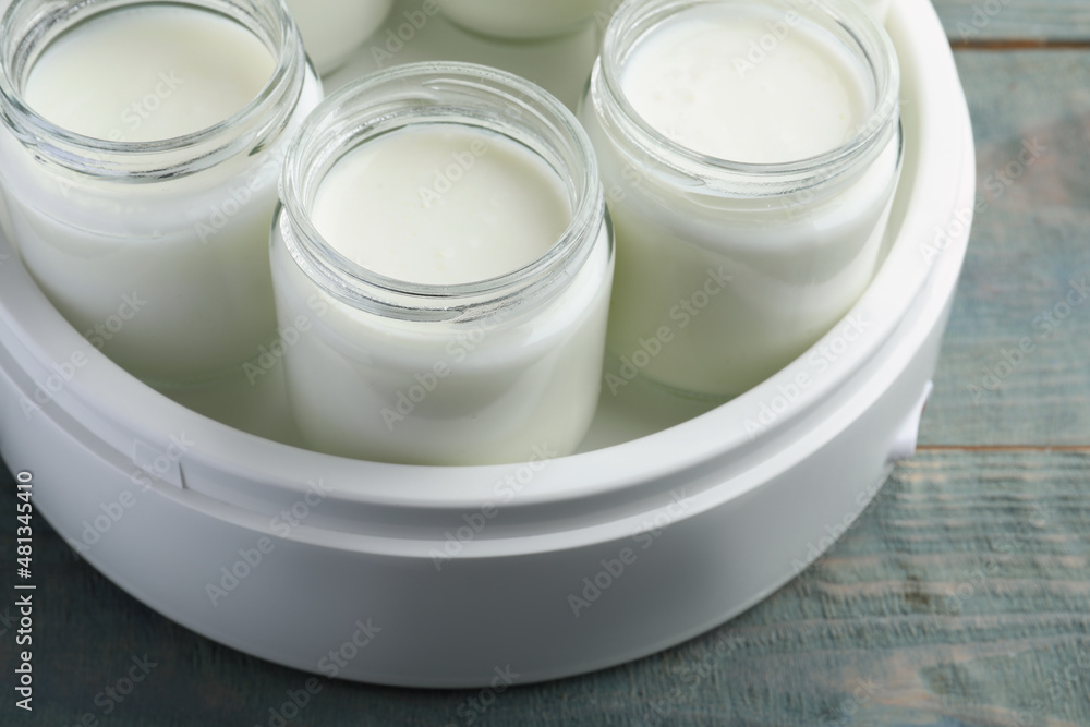 Modern yogurt maker with full jars on blue wooden table, closeup Modern yogurt maker with full jars on blue wooden table, closeup