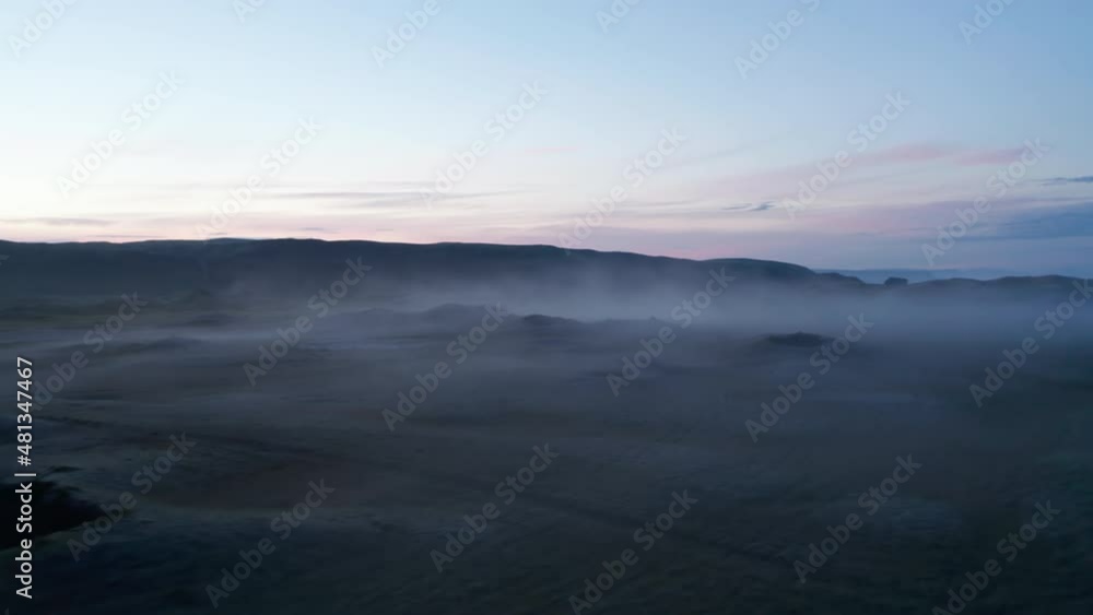 Low flight above Nordic landscape at dusk. Sparse mist rising from ground. Colourful twilight sky. Iceland Low flight above Nordic landscape at dusk. Sparse mist rising from ground. Colourful twilight sky. Iceland