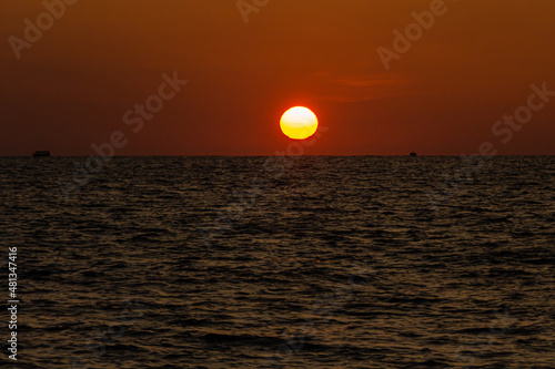 Fototapeta Naklejka Na Ścianę i Meble -  Beautiful orange sunrise is on the beach by the sea with black ship silhouettes