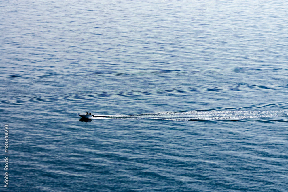 Boat in the water outside of Kullaberg, a natural reserve and mountain in the south of Sweden. Picture taken from high above, making the water pillar look very high. Boat going fast in Swedish-danish