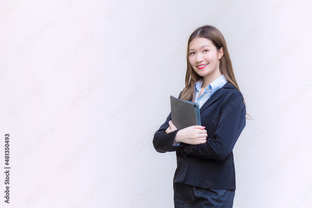 Asian business woman in black suit smiles happily while she works and holds tablet on white background. Asian business woman in black suit smiles happily while she works and holds tablet on white background.