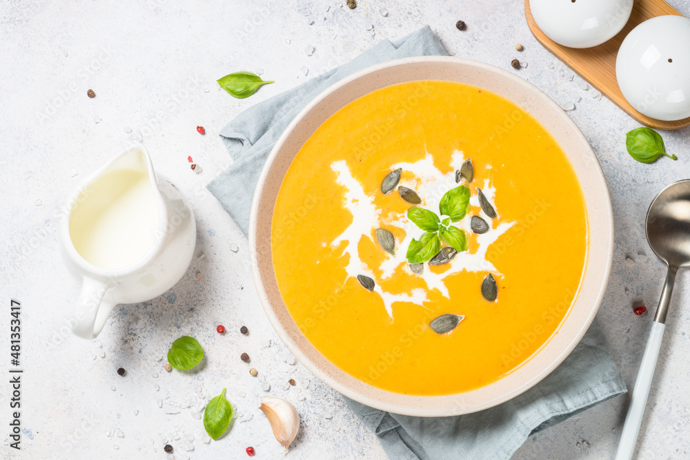 Pumpkin soup with cream. Top view image at white table.