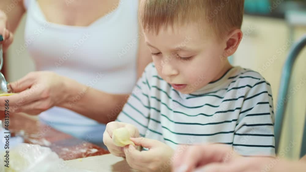 Family cooking in kitchen. Boy learn to make dough pies. Mom, grandmother and daughter skillfully make products from fresh dough. They have a lot of fun together. Family preparing pie dough. Family cooking in kitchen. Boy learn to make dough pies. Mom, grandmother and daughter skillfully make products from fresh dough. They have a lot of fun together. Family preparing pie dough.