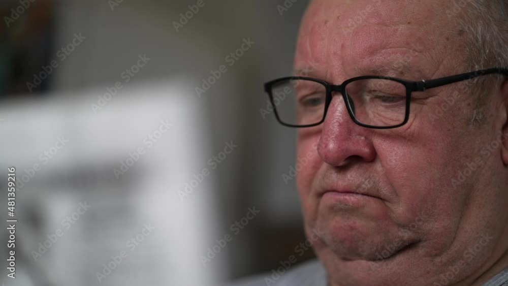 A mature man in glasses reading a newspaper at home. Senior Adult Reading Newspaper Leisure Concept. A mature man in glasses reading a newspaper at home. Senior Adult Reading Newspaper Leisure Concept.
