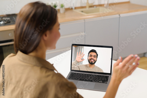 Close-up of asian woman with long hair using app for distance video communication with coworker, friend, meeting online, looking and waving at laptop desktop with male profile