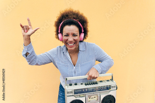 Senior african woman listening music in boombox vintage stereo - Focus on face