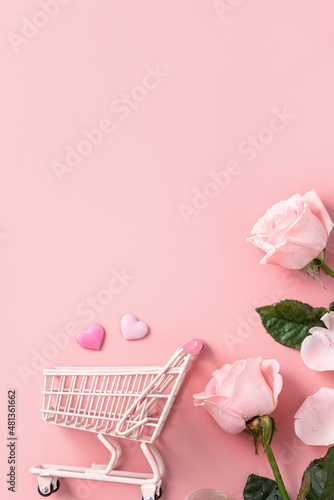 Valentine's Day shopping design concept background with pink rose flower and cart on pink background.