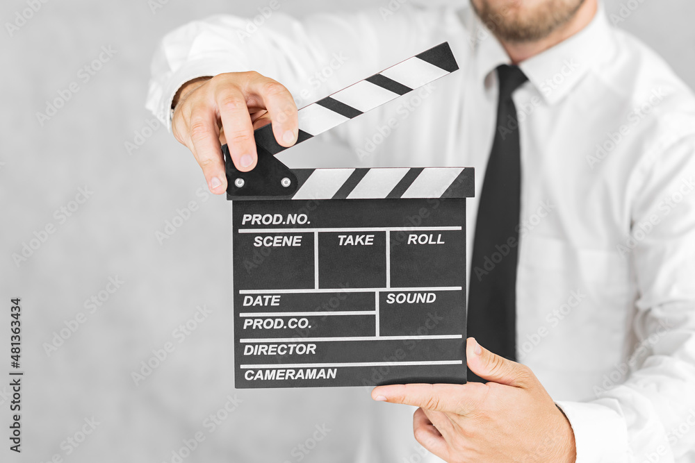 The director's clapperboard is in the hands of a man. On a light background. The director's clapperboard is in the hands of a man. On a light background.