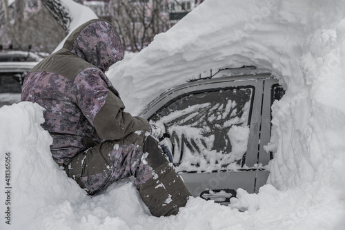 pensive man near a snow-covered car.Car covered with snow after a heavy snow storm