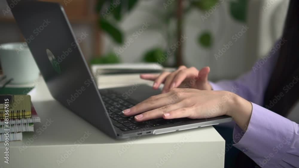 Closeup view of young woman typing on laptop keyboard and sitting at table in home room spbd. Beautiful female student looks at computer screen and types text, studies or works remotely and sits at Closeup view of young woman typing on laptop keyboard and sitting at table in home room spbd. Beautiful female student looks at computer screen and types text, studies or works remotely and sits at