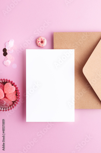 Mother's day, Valentine's day, Birthday party invitation or greeting template with empty card for your design. Festive confetti, candy hearts, blank paper and envelope from above on pink background.