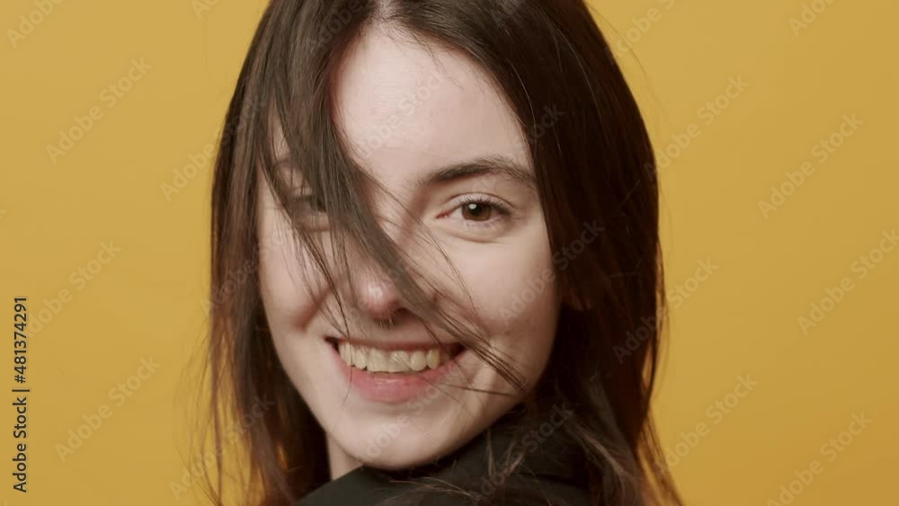 The young woman with flying hair looks on with a smile, happy. touches her hair The young woman with flying hair looks on with a smile, happy. touches her hair