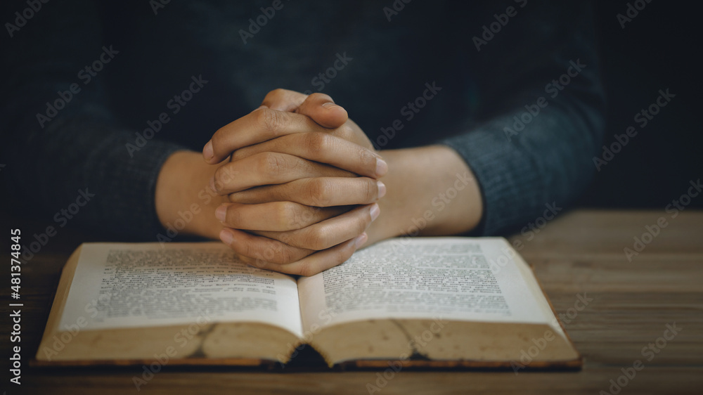 Naklejka premium Christian life crisis prayer to god. Women Pray for god blessing to wishing have a better life. Hands praying to god with the bible. believe in goodness. Holding hands in prayer on a wooden table.