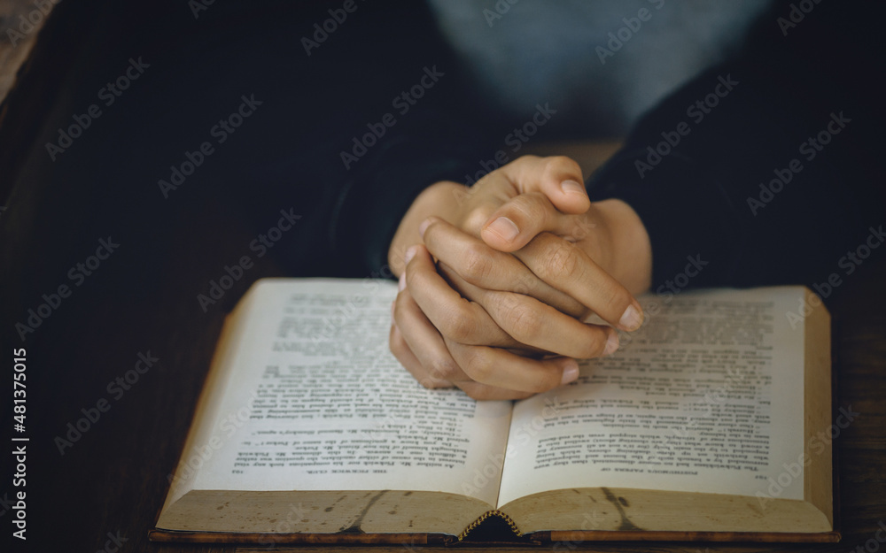 Naklejka premium Christian life crisis prayer to god. Women Pray for god blessing to wishing have a better life. Hands praying to god with the bible. believe in goodness. Holding hands in prayer on a wooden table.
