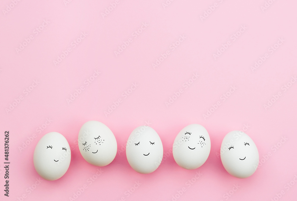 Easter eggs with cute faces painted on a delicate pink background. The concept of the Easter holiday. Top view. Easter eggs with cute faces painted on a delicate pink background. The concept of the Easter holiday. Top view.