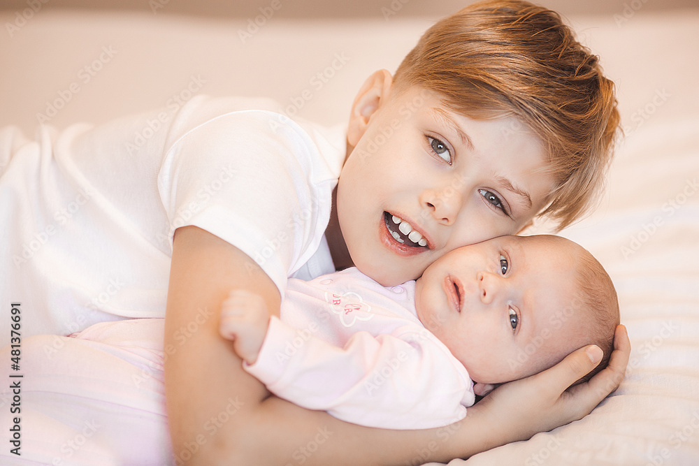 Little brother boy holding his newborn sister. Infant and child indoors. Little brother boy holding his newborn sister. Infant and child indoors.