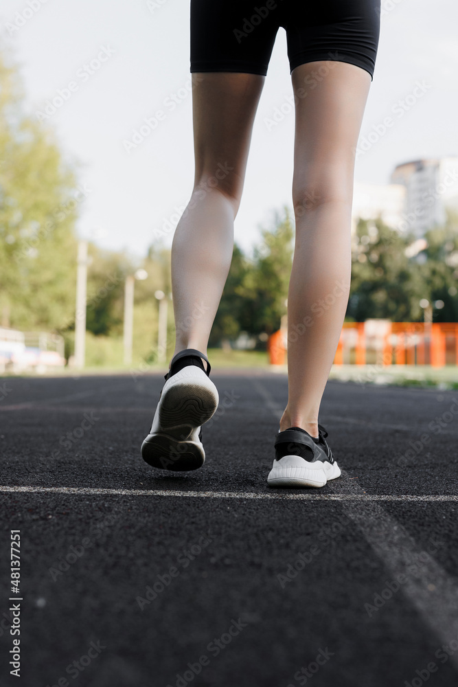A beautiful, slender girl runs on a special coating on the street. Running in the park on a treadmill. The concept of an active lifestyle. close-up on shoes