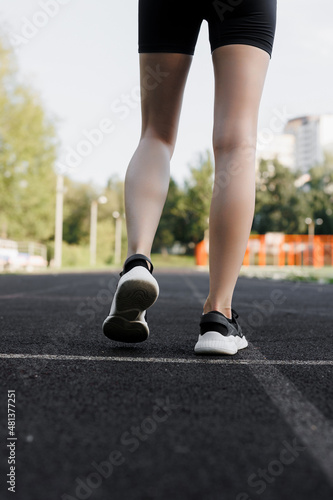 A beautiful, slender girl runs on a special coating on the street. Running in the park on a treadmill. The concept of an active lifestyle. close-up on shoes © Anna