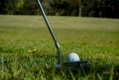 Golf clubs and ball on a green lawn in a beautiful golf course with morning sunshine.