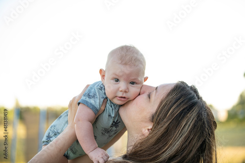 Niño bebé en brazos de su madre siendo besado