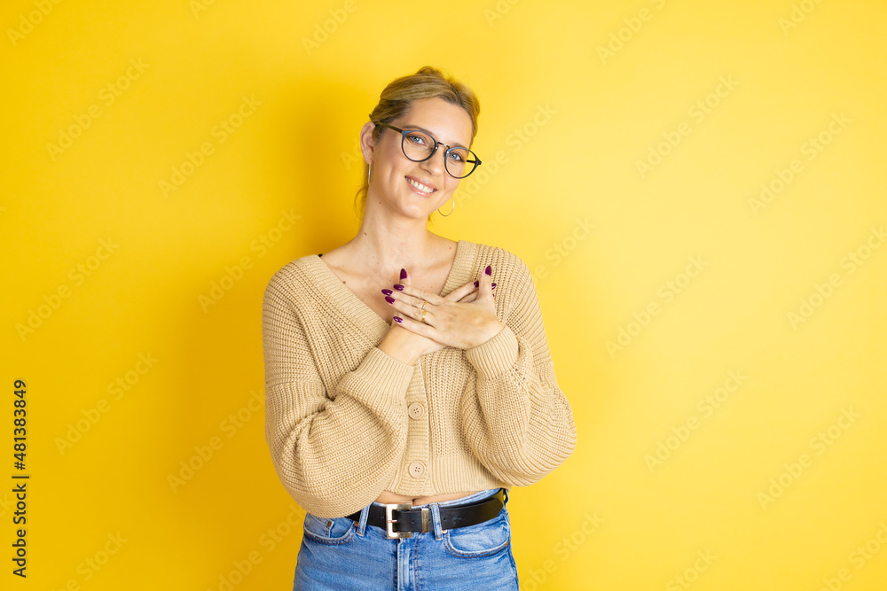 Young beautiful woman wearing casual sweater over isolated yellow background smiling with her hands on her chest and grateful gesture on her face.