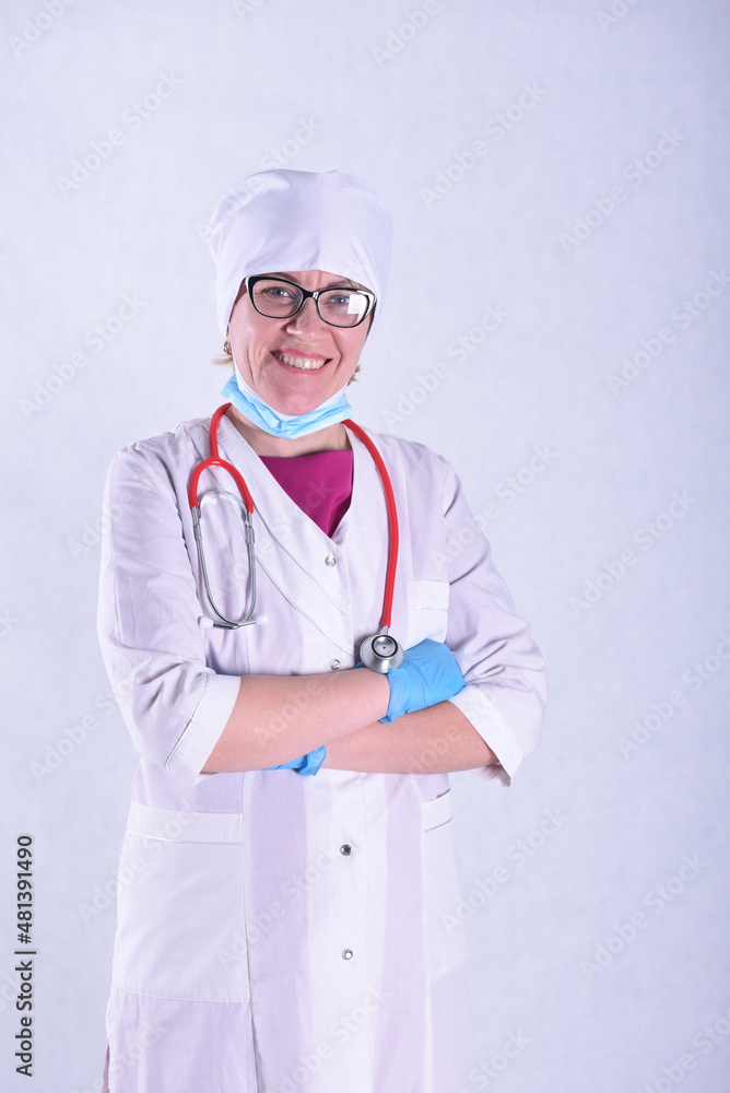 A female doctor in a white coat and headdress wearing optical glasses with a stethoscope on a white background A female doctor in a white coat and headdress wearing optical glasses with a stethoscope on a white background