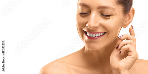 Skin care concept - close-up portrait of a 40 years old woman with closed eyes touching her skin.