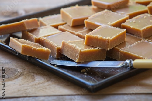 Fotografía Homemade fudge squares on a baking sheet in warm sunlight on an old wooden table