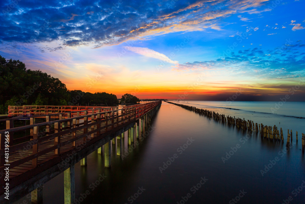 Sunrise and beautiful sky background at wooden red bridge over the sea at Gulf of Thailand, near by Tha Chin estuary, Samutsakhon province, Thailand 