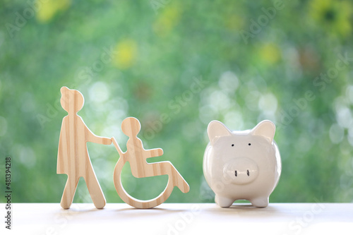 Employee volunteer assistant with man on wheelchair and piggy bank on natural green background,Save money for prepare in future and handicapped person concept