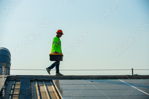 worker  walk on rooftop of factory  with hold tool box to service  Solar panel. 