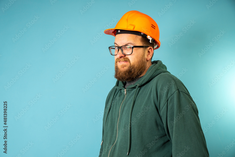 Cute Caucasian bearded construction worker with safety helmet on head shows thumb up. Engineer in orange helmet isolated on background. Construction worker concept . Cute Caucasian bearded construction worker with safety helmet on head shows thumb up. Engineer in orange helmet isolated on background. Construction worker concept .