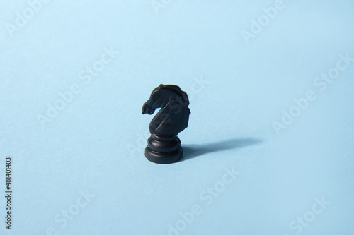Black chess knight on a blue background. Abstract background. Chess piece. Concept of leadership, loneliness