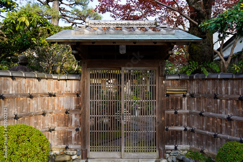 Japanese traditional entance gate to beautiful and peaceful garden in front old Japanese house, cover of big maple tree with morning sunrise in Japan house village. photo