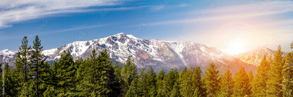 Panoramic landscape scene with sun shining behind the snow capped mountains in Lake Tahoe California