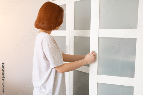 Female open the wardrobe doors in sunny morning at her bedroom