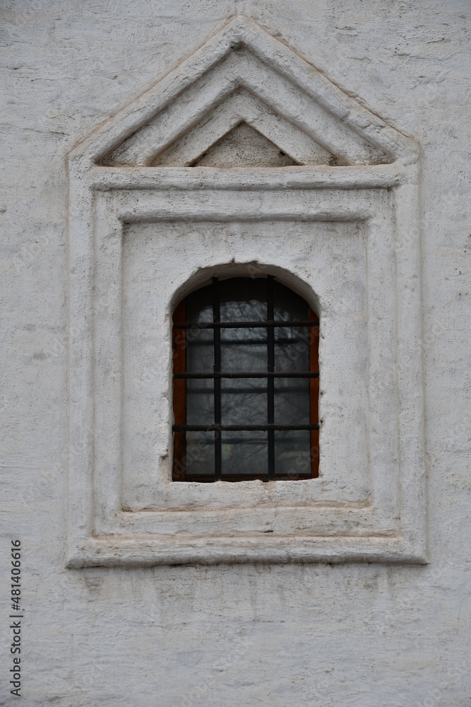 Window in an old building. White wall with a window and carved stone architraves.