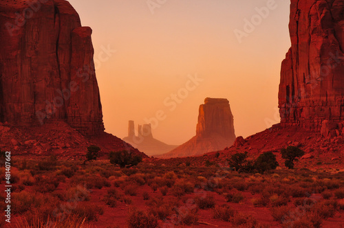 Hazy red sunset view of the North Window, between Elephant Butte and Cly Butte, towards East Mitten Butte and other spires and towers of Monument Valley Navajo Tribal Park, Arizona, Southwest USA © Pedro