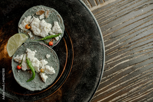 Black tortillas with queso fresco on black plate