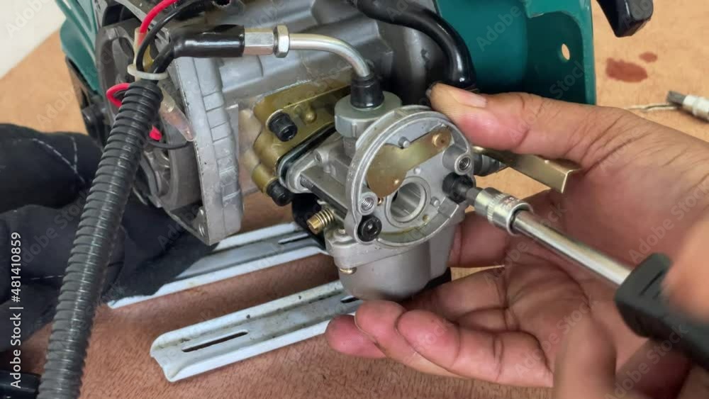 A young man is repairing a small two-stroke engine used for farming. disassemble the parts cleaning the carburetor Reassemble and test A young man is repairing a small two-stroke engine used for farming. disassemble the parts cleaning the carburetor Reassemble and test
