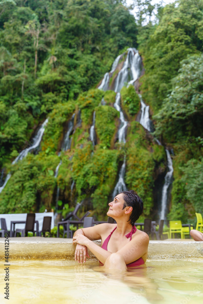 Fototapeta premium Vertical view of latin american woman at thermal springs in Colombia. Cropped view of woman at jungle waterfalls in Santa Rosa Cabal valley. Colombia travel destination and relax concept.