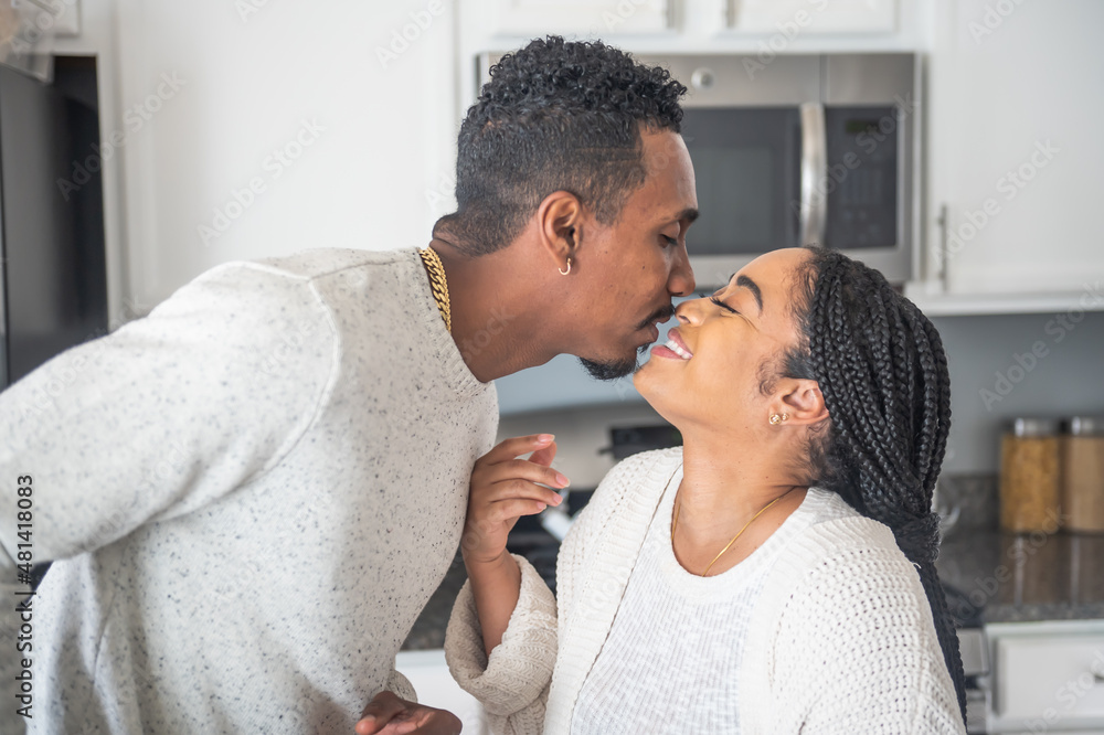 Fototapeta premium Smiling couple kissing in kitchen