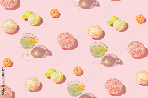 Creative pattern made of exotic cocktail in crystal glass and citrus fruits on pink background. Minimal summer concept.