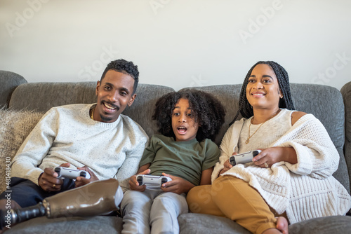 Boy  playing video game with mother and father with prosthetic leg