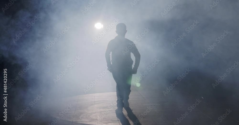 silhouette of a female dancer performing hip hop dance in slow motion with light and smoke background silhouette of a female dancer performing hip hop dance in slow motion with light and smoke background
