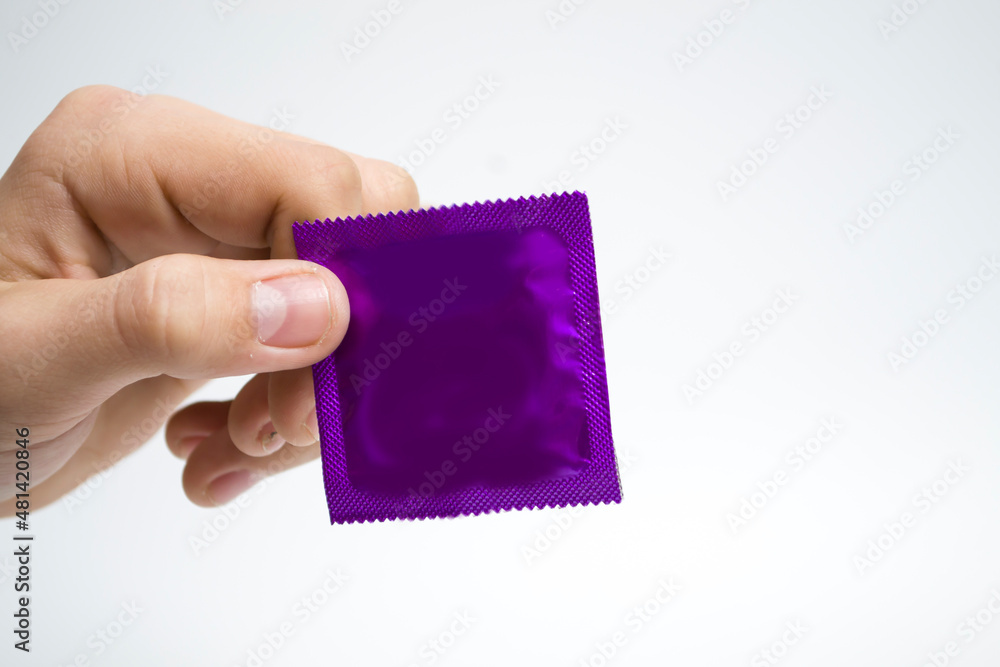Obraz premium Hand pack blue condom on a white background, concept protection against AIDS.