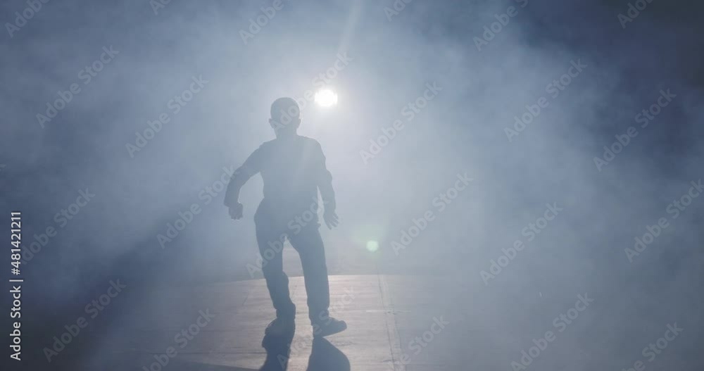 silhouette of a female dancer performing hip hop dance in slow motion with light and smoke background silhouette of a female dancer performing hip hop dance in slow motion with light and smoke background
