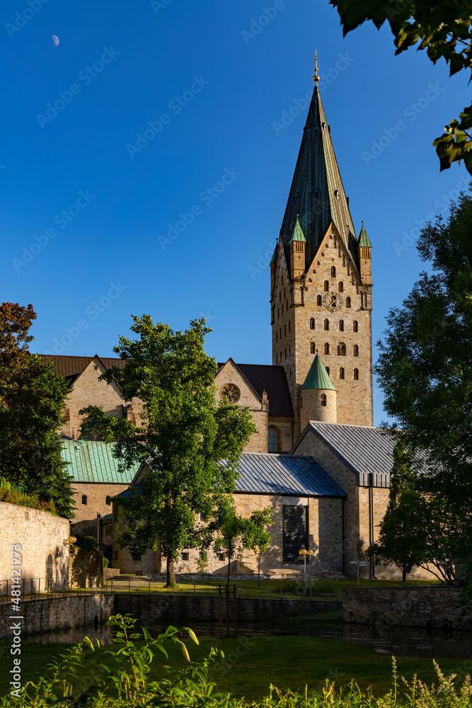 Paderborn Cathedral in Westphalia Germany with impressive big bell tower on a blue sky summer day. Catholic church monument and tourist pilgrim attraction, near Pader sources in historic town centre.