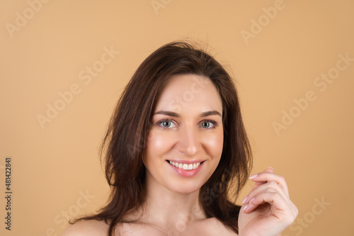 Close beauty portrait of a topless woman with perfect skin and natural makeup, shiny lips, on a beige background