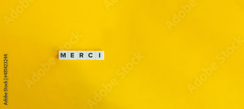Tela Merci Word on Letter Tiles on Yellow Orange Background